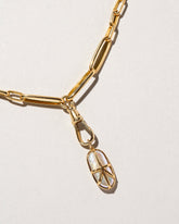 Closeup details of the Grand Swivel Fob paired with the Long Loop Chain Necklace and charm on light color background.