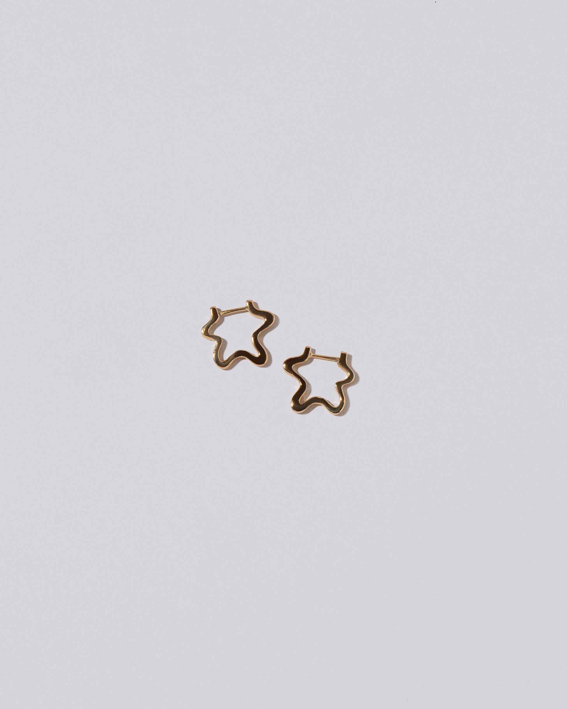 Snow Flower Huggie Hoops on light color background.