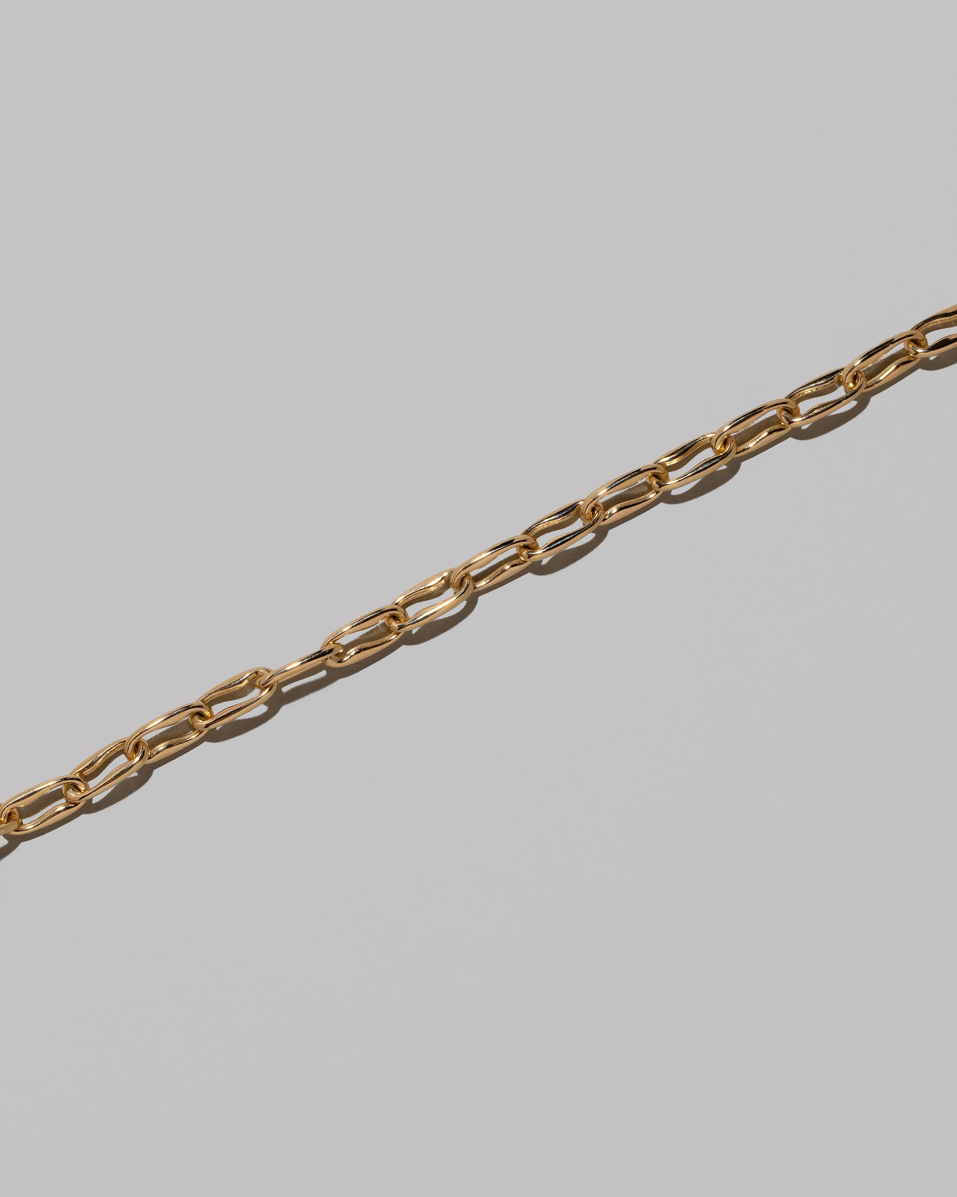 Closeup details of the Wavy Link Chain Bracelet on light color background.