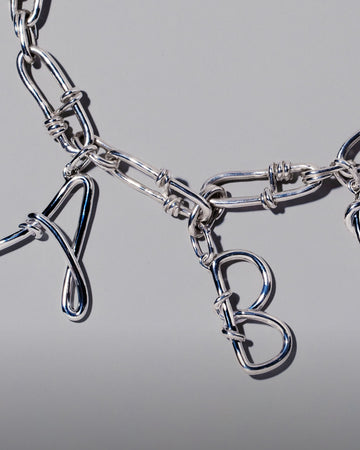 CRZM Large Sterling Silver Letter Charm A, CRZM Large Sterling Silver Letter Charm B and CRZM Sterling Silver Canyon Necklace on light color background.