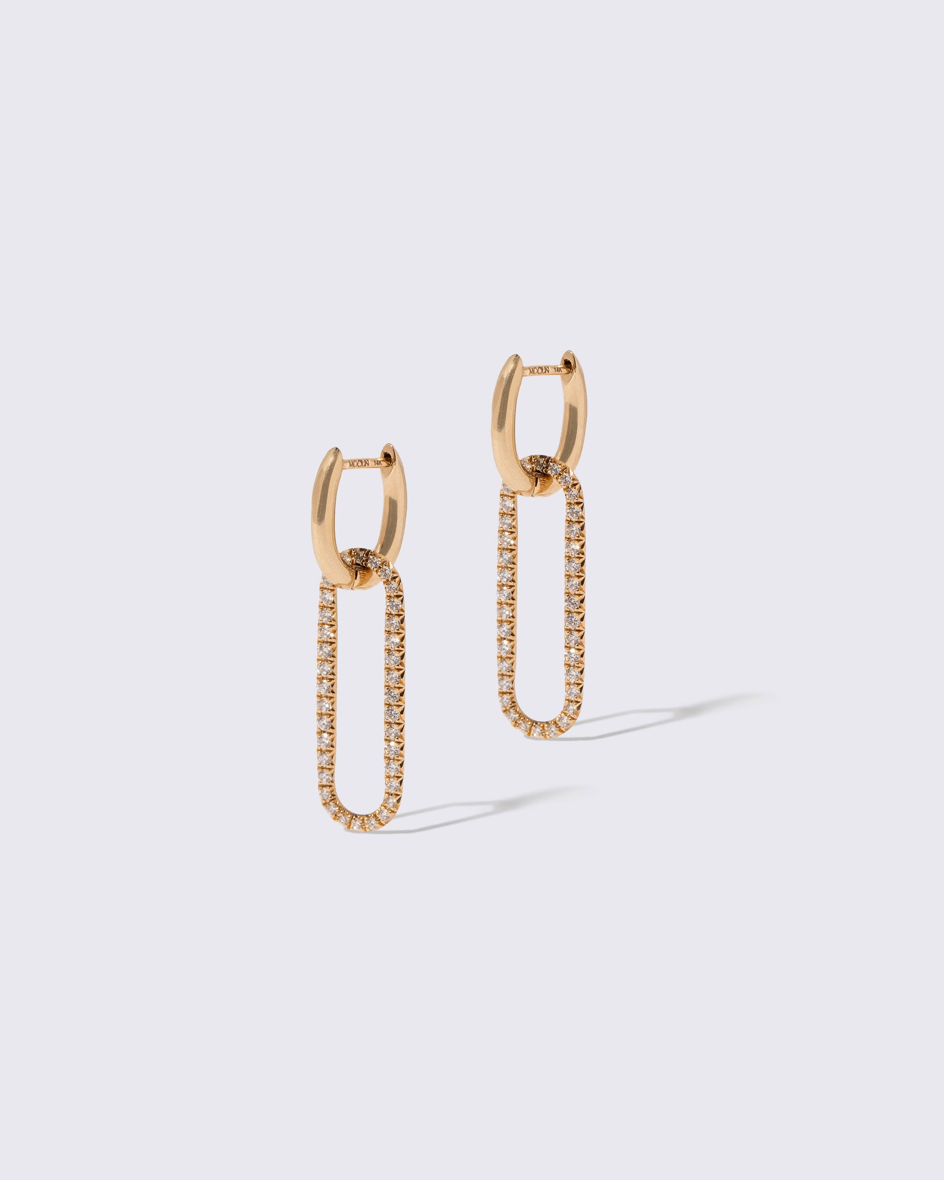 Pavé Link Huggie Hoop Earrings on light color background.