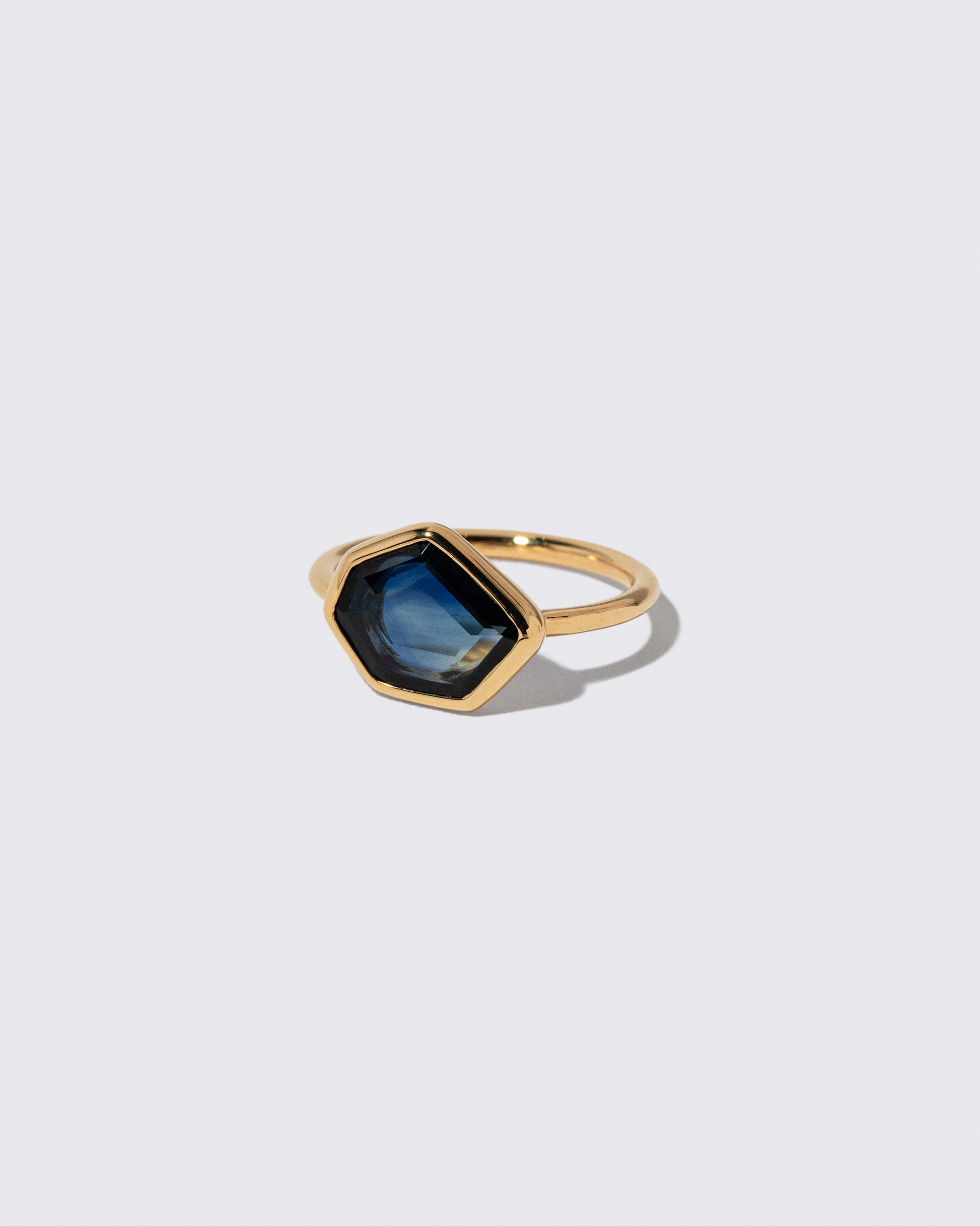 View from the side of the Teal Blue Sapphire Gusher Ring on light color background.