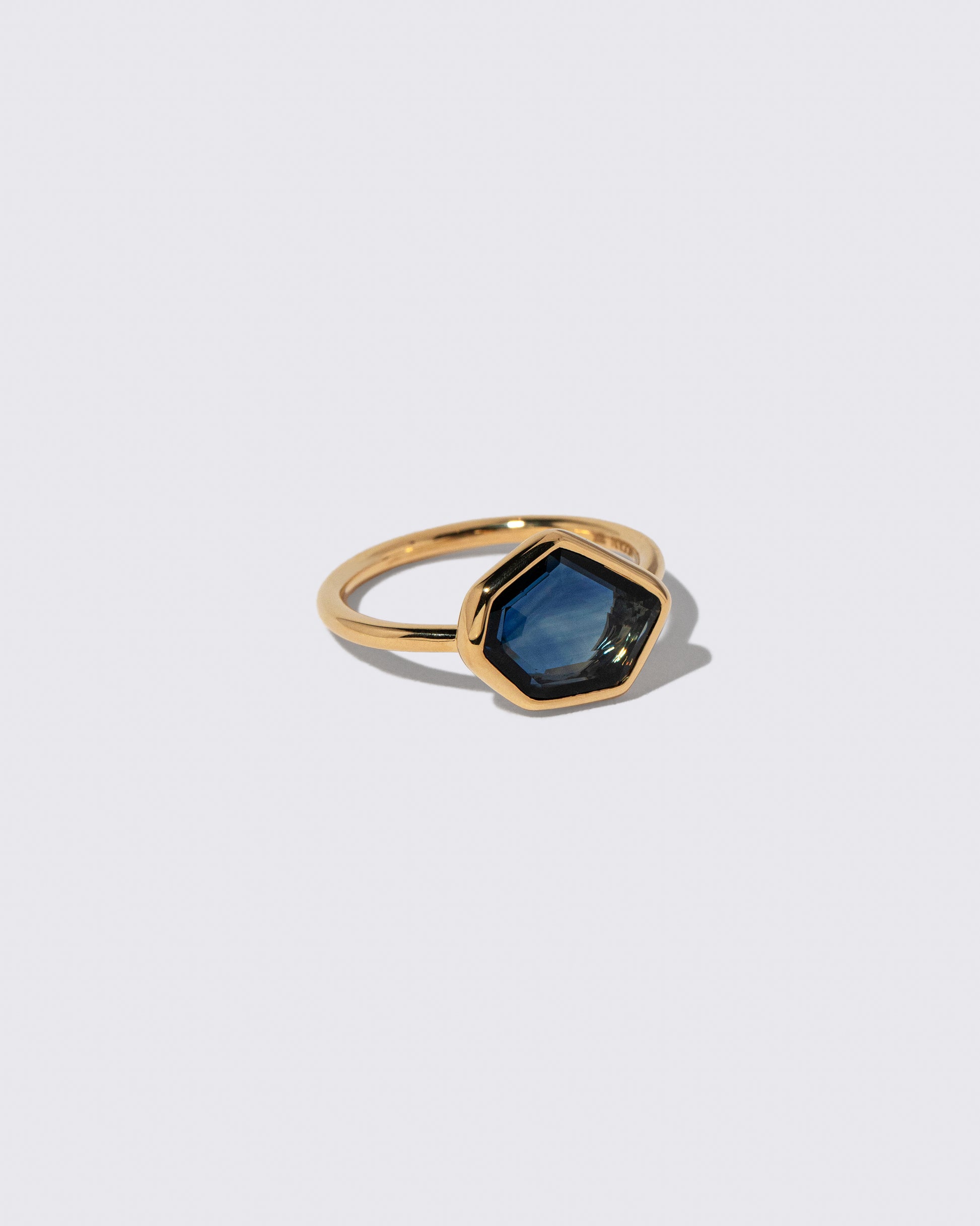 View from the side of the Teal Blue Sapphire Gusher Ring on light color background.