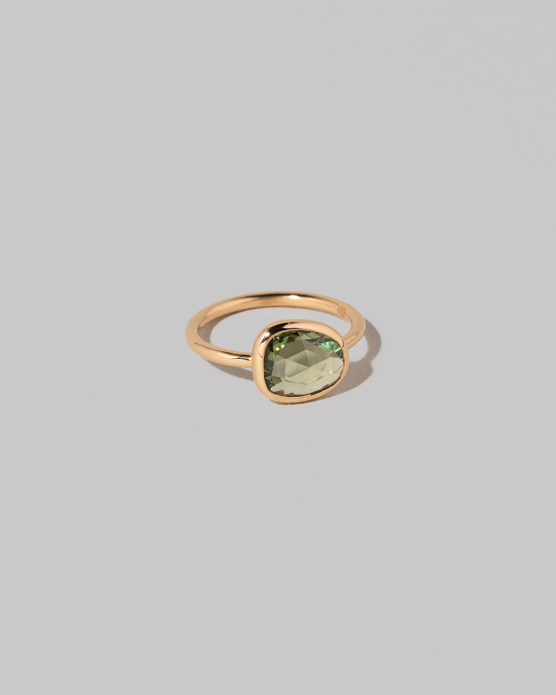 View from the side of the Gusher Green Sapphire Ring 004 on light color background.