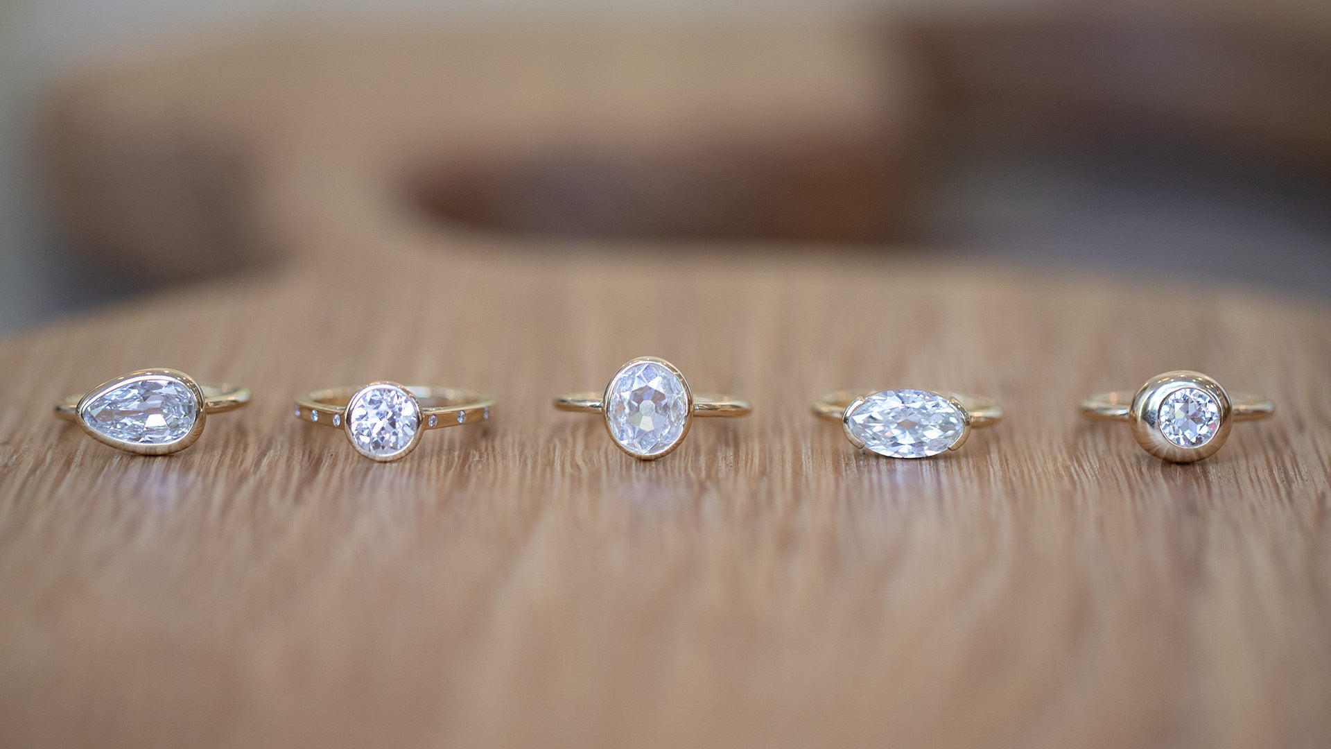 Styled image featuring mixed Mociun diamond solitaires on wood table.