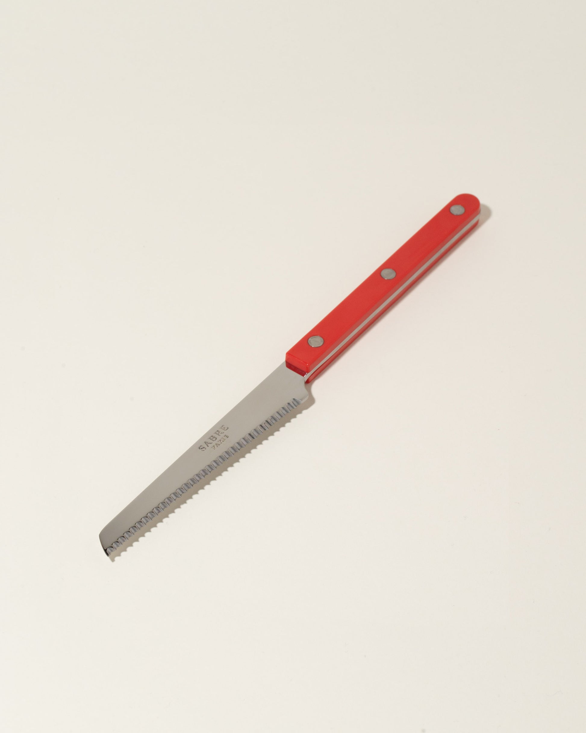 Sabre Paris Red Tomato Knife on light color background.