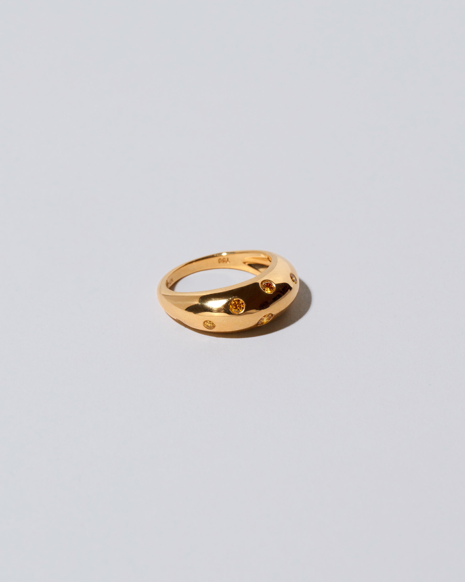 View from the side of the Gold Yellow Diamond Brilliant Cuts Light Cutter Band on light color background.