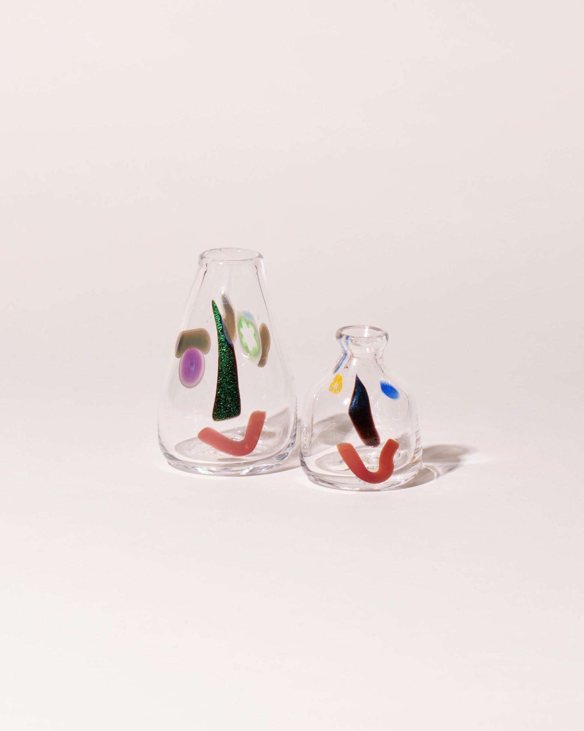 Group of FACEVESSEL Bud Vases on light color background.