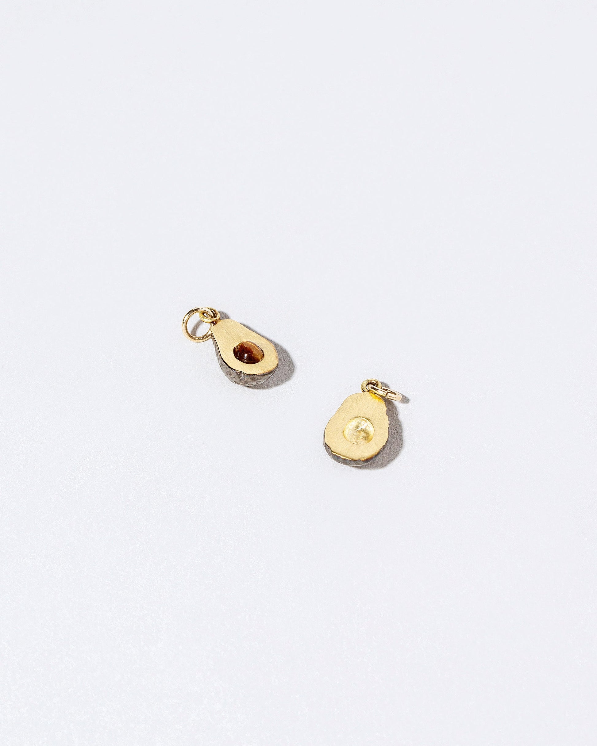 Closeup details of the Halved Avocado Charms on light color background.