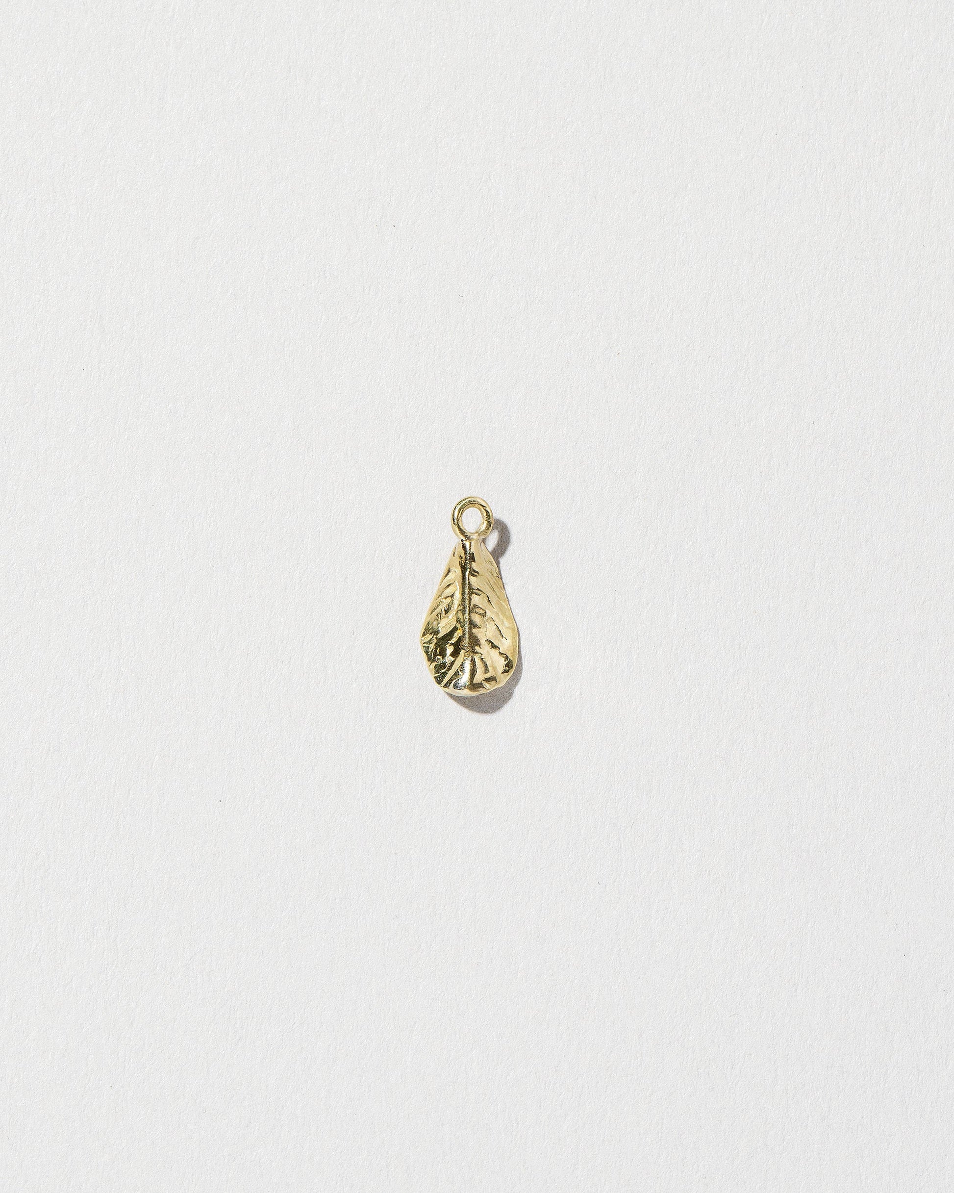 View from the back of the #5 Arugula Charm on light color background.