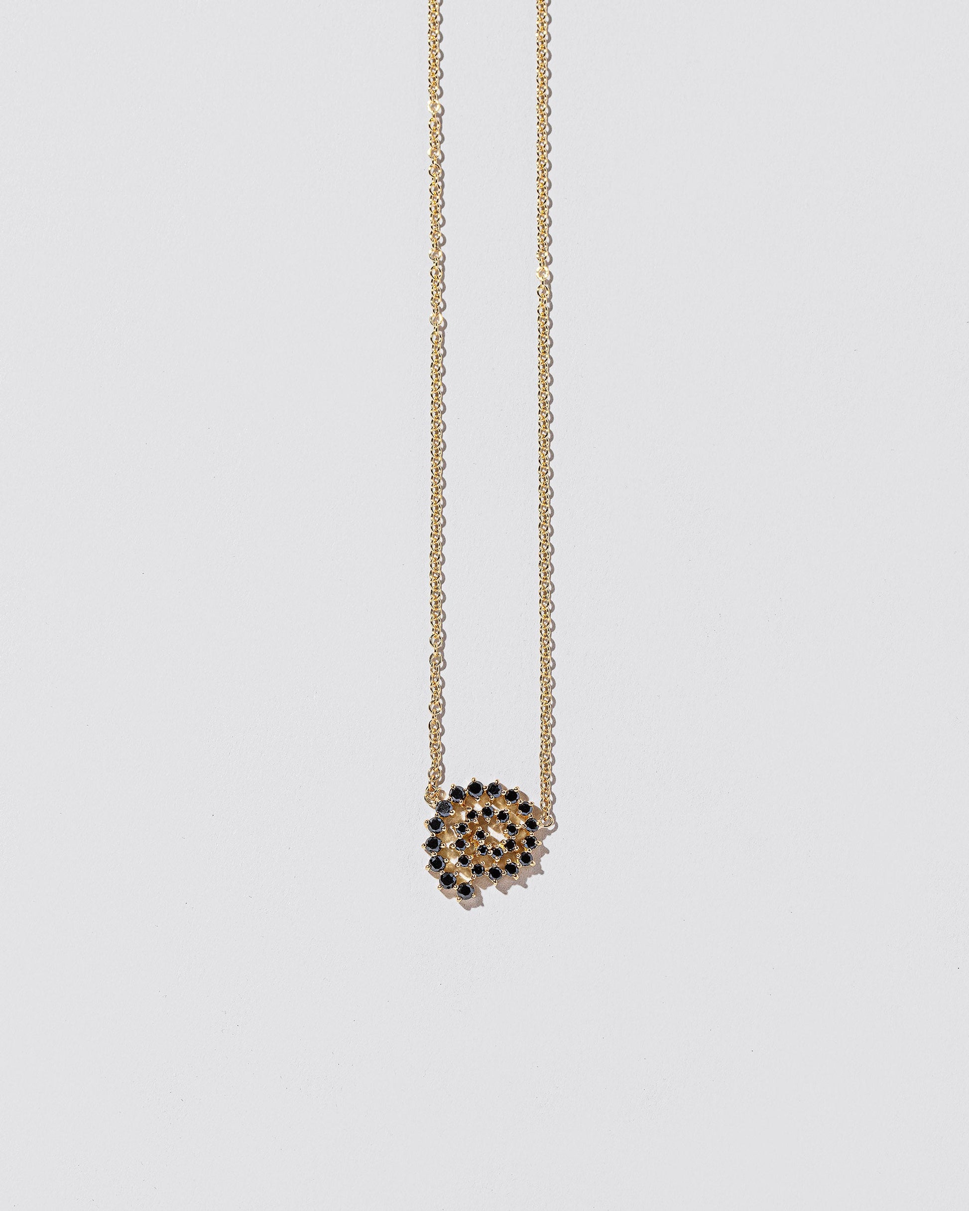 Closeup details of the Full Black Diamond Spiral Necklace on light color background.
