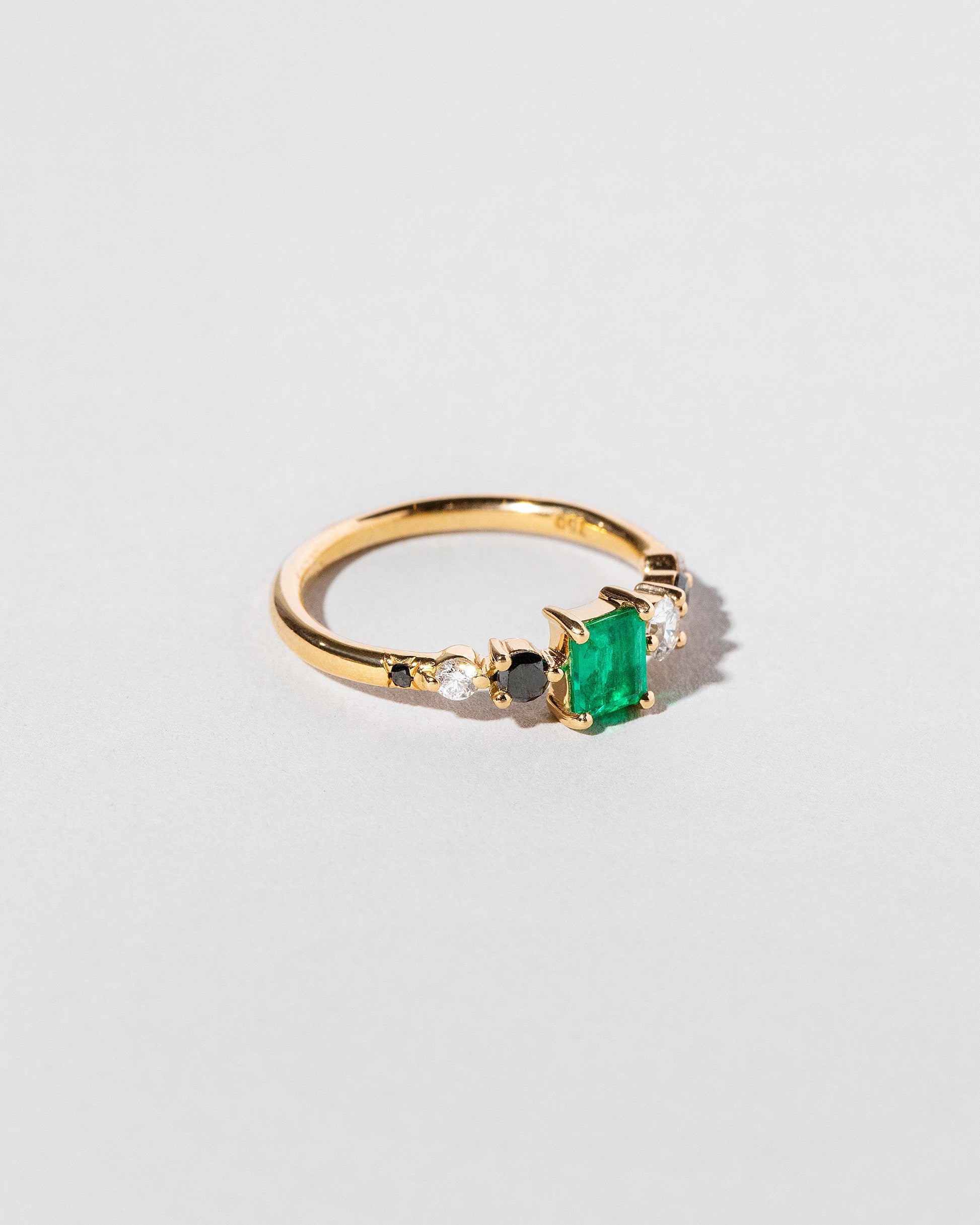 View from the side of the Emerald Seven Sisters Ring on light color background.