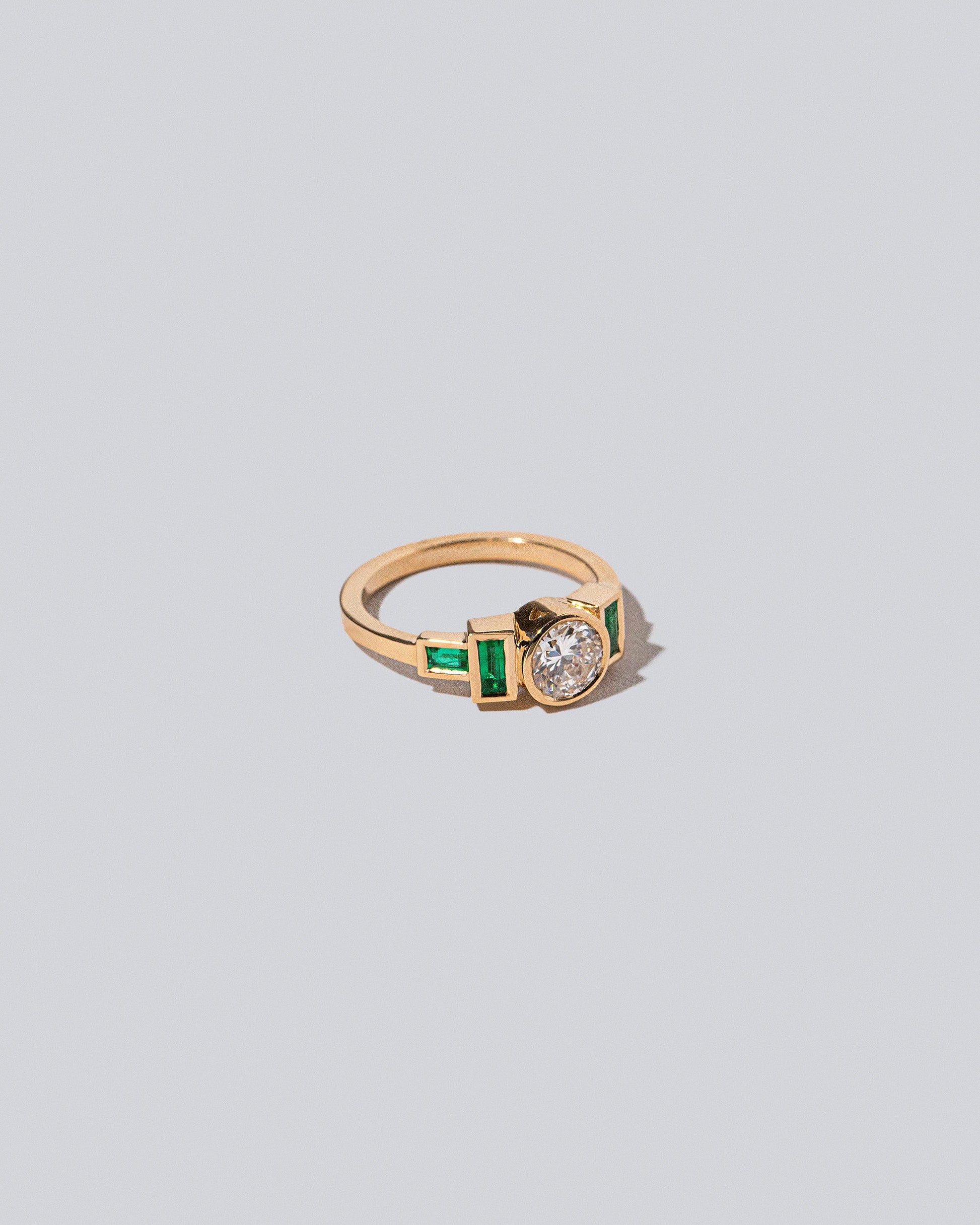 View from the side of the Diamond & Emerald Third Eye Ring on light colored background.