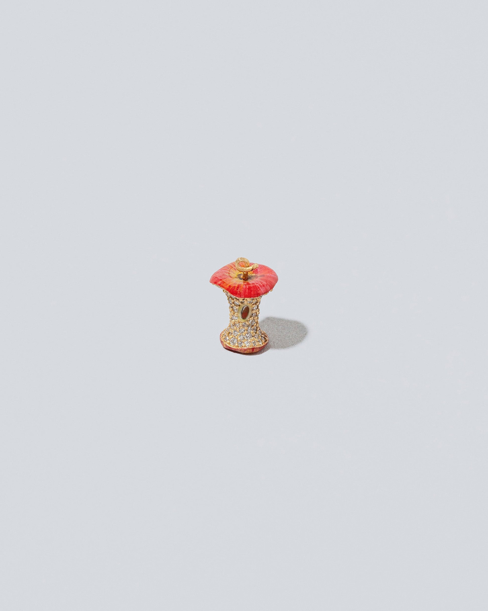 Closeup details of the Red Apple Core Charm on light color background.